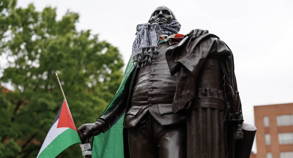 A statue is of George Washington covered with a Palestinian flag and a keffiyeh by protestors at The George Washington University in Washington, D.C., April 25, 2024. Photo credit: Bryan Olin Dozier via Reuters Connect.