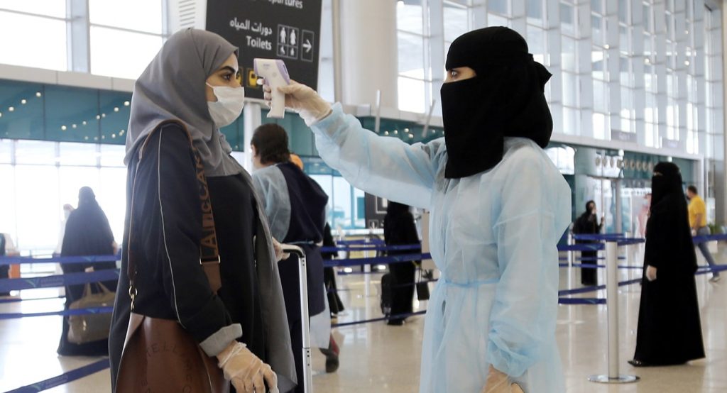 A security woman checks the temperature of a woman in Saudi Arabia. Photo credit: REUTERS.