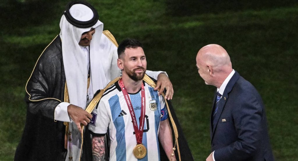 The Emir of Qatar, Sheikh Tamim bin Hamad Al Thani, puts on Argentina's Lionel Messi a "bisht", a traditional Arab garment, in front of Fifa President Gianni Infantino before handing over the World Cup trophy. Photo credit: Robert Michael/dpa