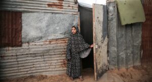 A Palestinian girl stands outside her family's home in a poor neighborhood in Beit Lahia, northern Gaza Strip, December 2022. Photo credit: Majdi Fathi via Reuters Connect.