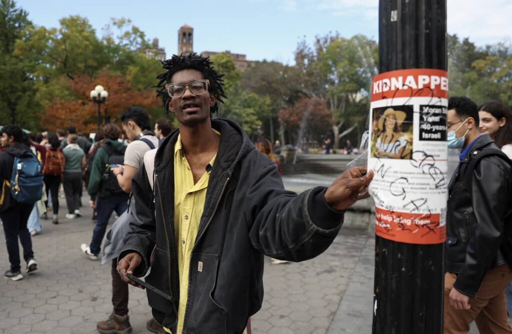 A man rips off a poster with a picture of an Israeli woman kidnapped by Hamas, at a pro-Palestinian demonstration by students of New York University, October 25, 2023. Photo credit: REUTERS/Shannon Stapleton.