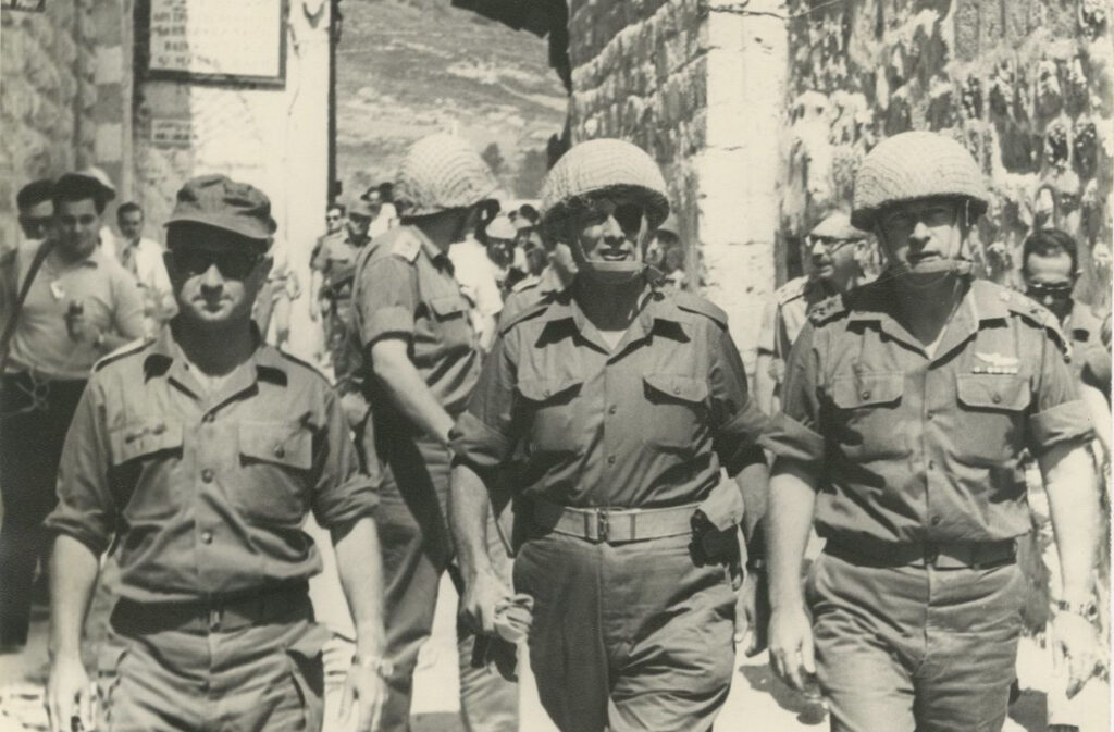 Defense Minister Moshe Dayan,  IDF Chief of Staff Yitzhak Rabin (R) and Central Command Chief Uzi Narkis (L) enter the Old City of Jerusalem, June 7, 1967 [behind them, IDF Deputy Operations Chief Rehavam Zeevi turns around at the sound of Jordanian sniper fire]. Photo credit: Ilan Bruner.