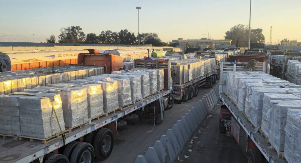 Trucks carrying humanitarian aid line up at the Rafah border, October 2025. Photo credit: REUTERS.
